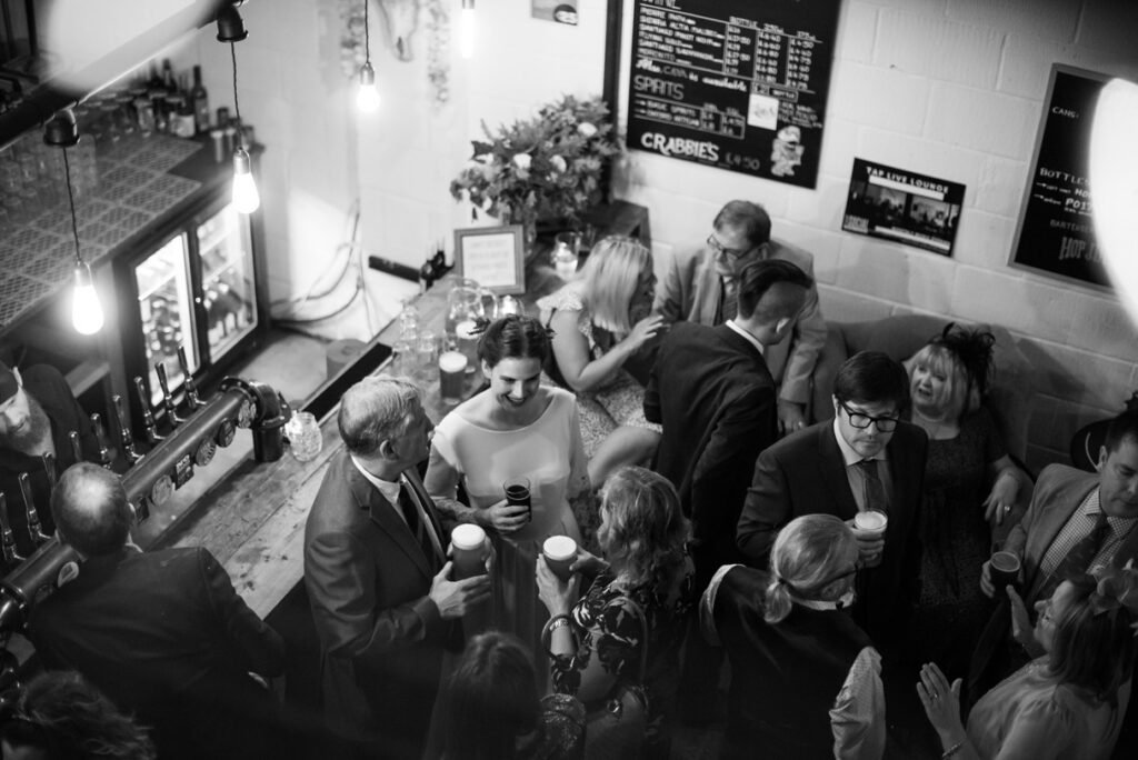 Guests packed into a pub bar after the wedding, black and white photograph