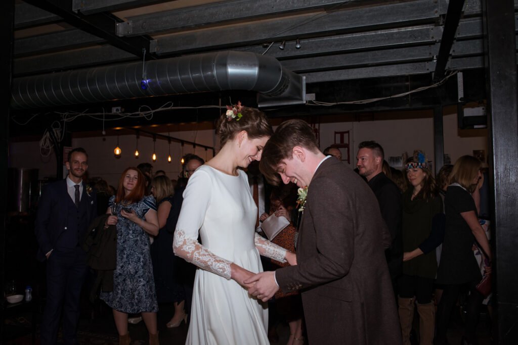 Bride and groom holding hands and laughing among their guests at the reception