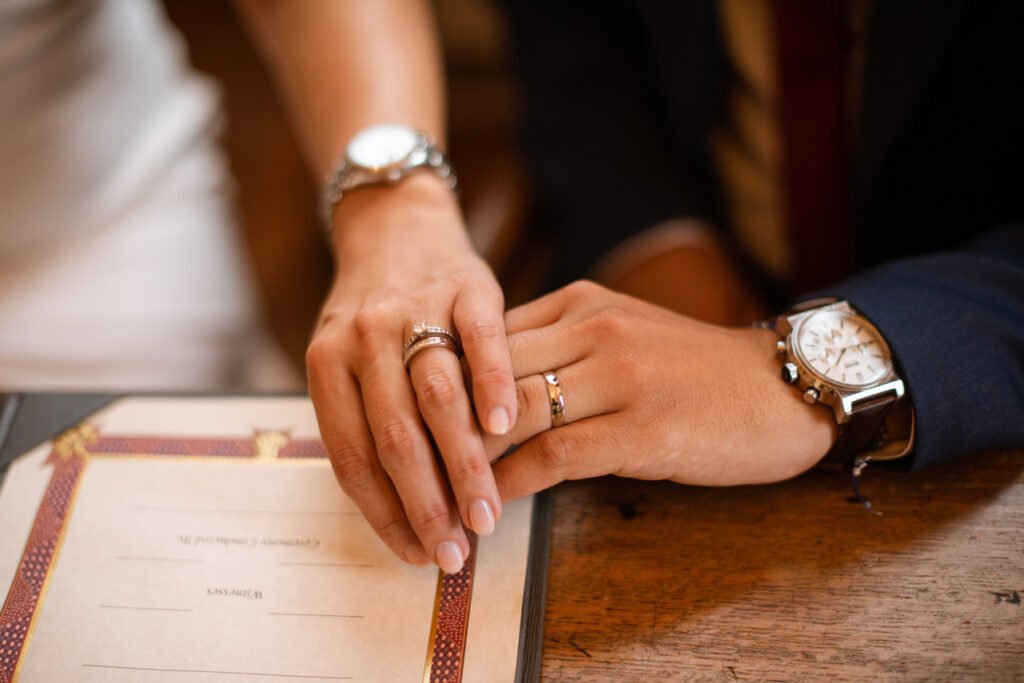 Bride's hands resting over her husband's on the marriage register