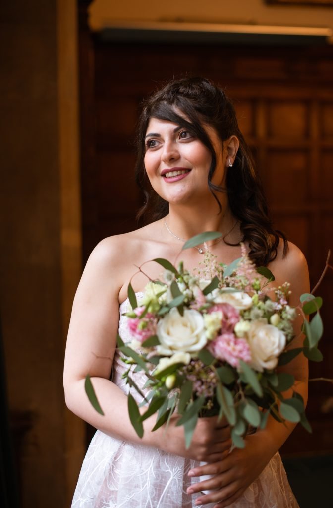 Bride holding a garden rose bouquet in a panelled doorway