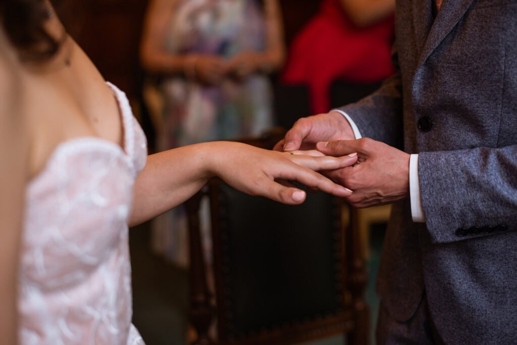Close view of the ring being placed on the bride's finger