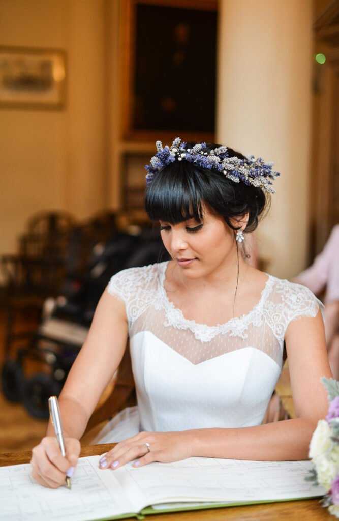 Bride in a lavender flower crown signing the wedding register