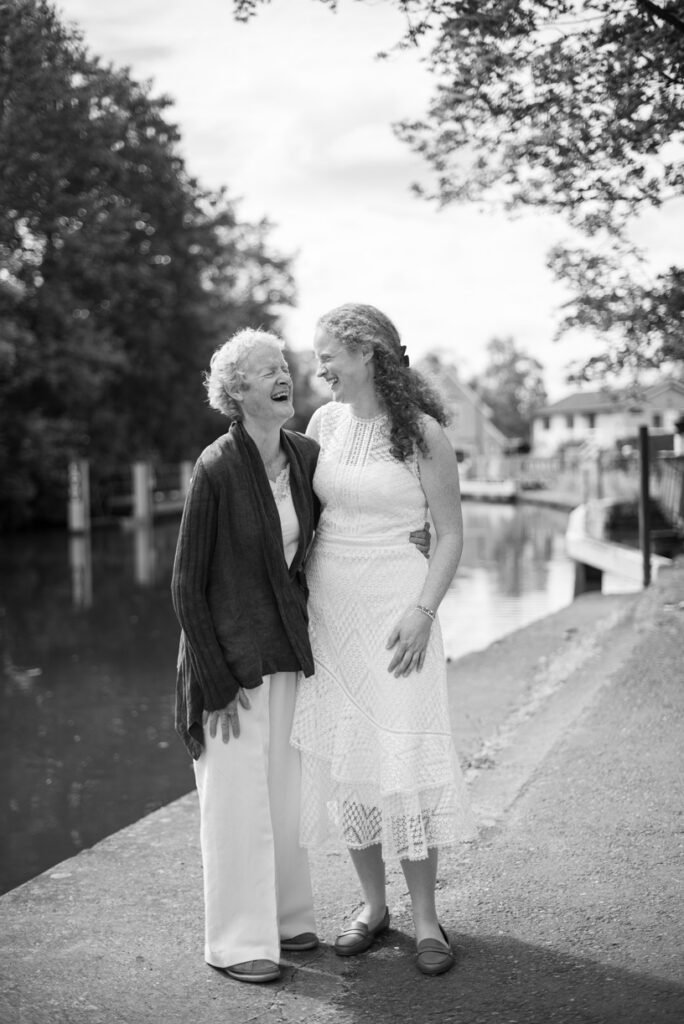 Bride and her grandmother laughing together by the river, black and white photograph