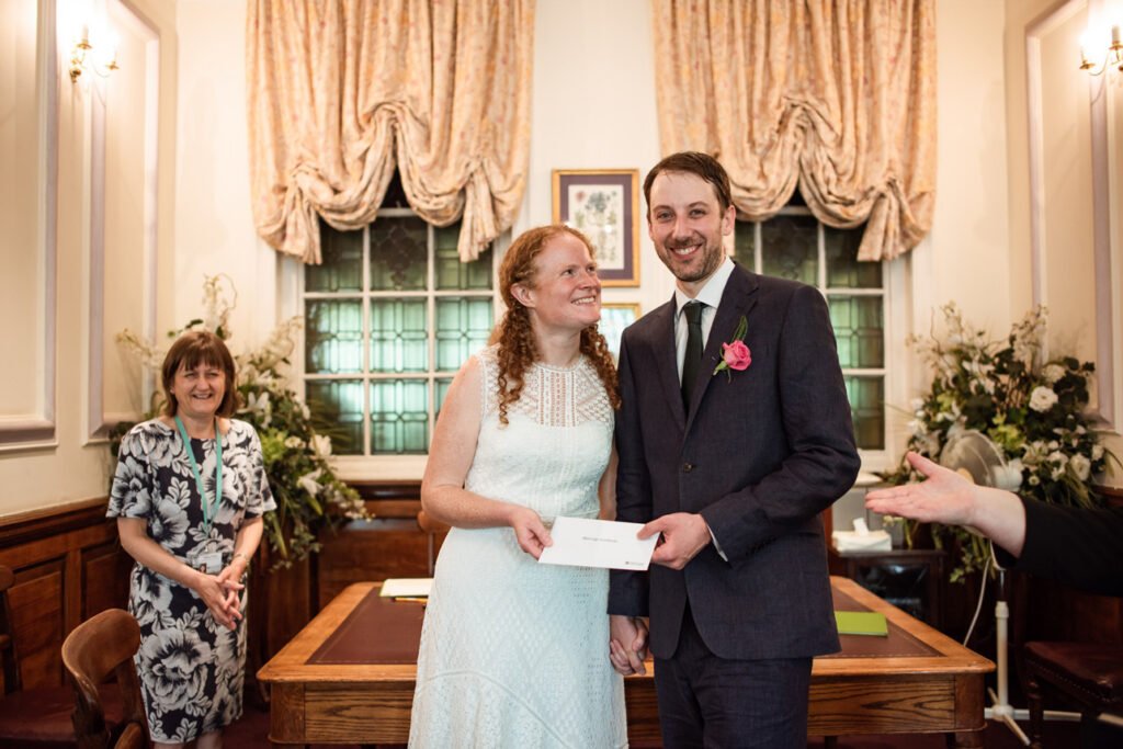 Bride and groom holding their marriage certificate in the ceremony room