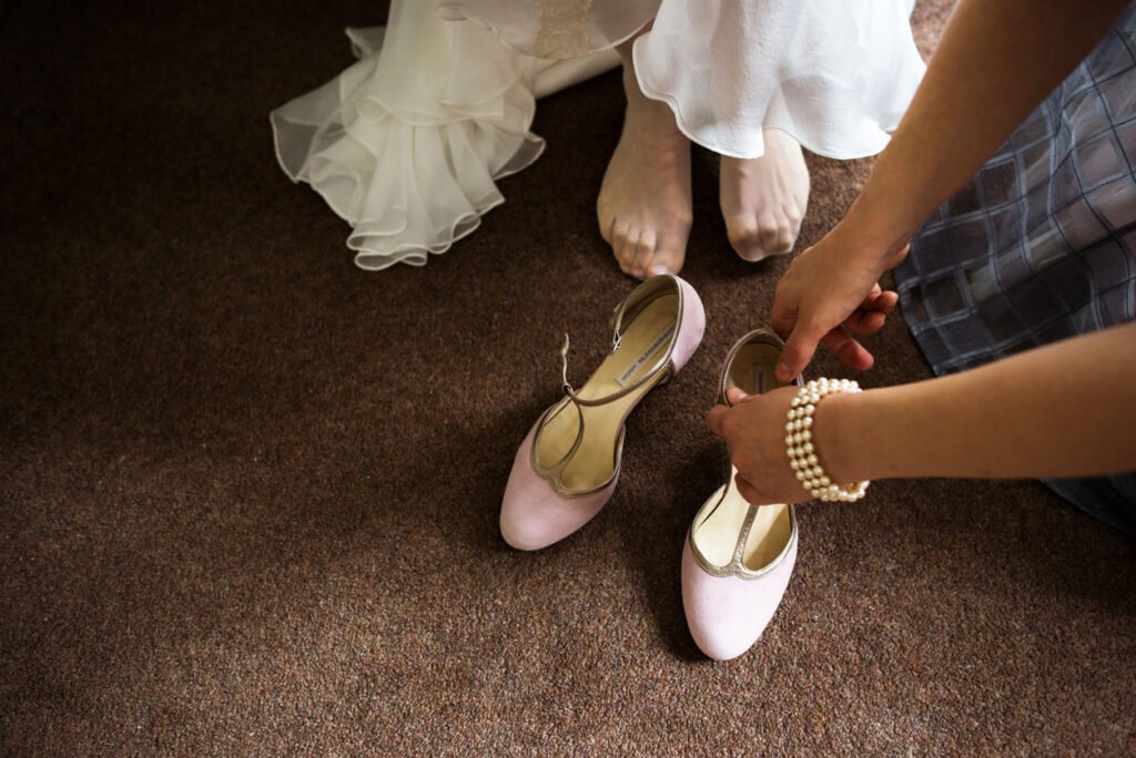 Bride's hand and pale pink shoes on the floor before the ceremony