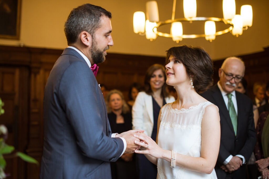 Bride and groom exchanging rings in front of their guests at the register office